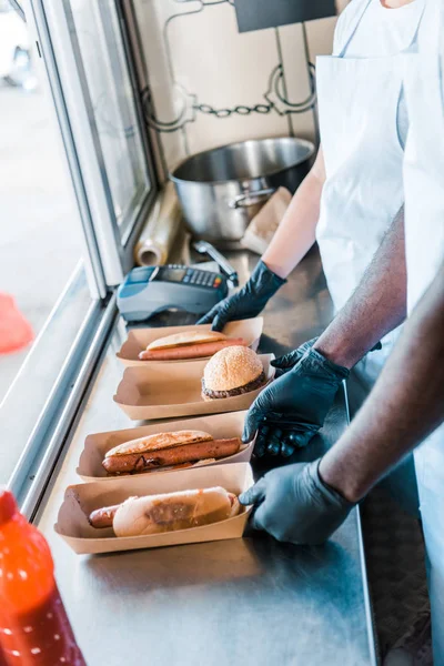 Vista ritagliata di chef multiculturali che tengono piatti di cartone con cibo di strada — Foto stock