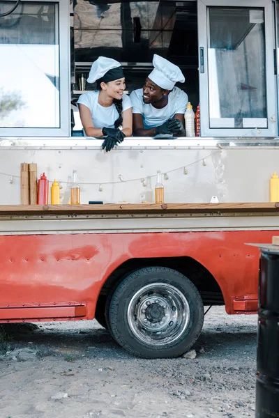 Happy asian girl looking at african american man in food truck — Stock Photo