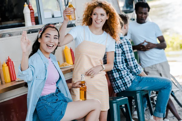 Selective focus happy asian girl waving hand near redhead woman and food truck — Stock Photo