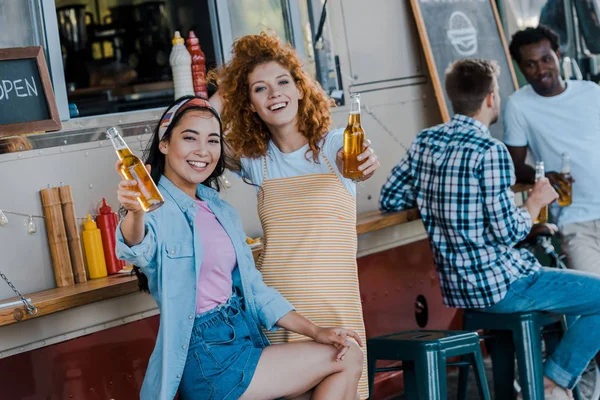 Selettivo fuoco di felice asiatico ragazza holding birra vicino rossa donna e cibo camion — Foto stock