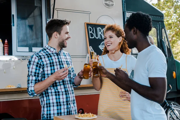 Selektiver Fokus gutaussehender multikultureller Männer, die in der Nähe eines Food-Trucks mit einer rothaarigen Frau klirren — Stockfoto