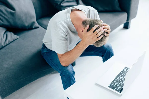 Aus der Vogelperspektive: Mann im T-Shirt berührt Kopf in Wohnung — Stockfoto