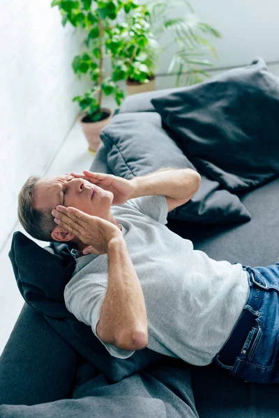 Homem bonito em t-shirt com olhos fechados tocando cabeça no apartamento — Fotografia de Stock