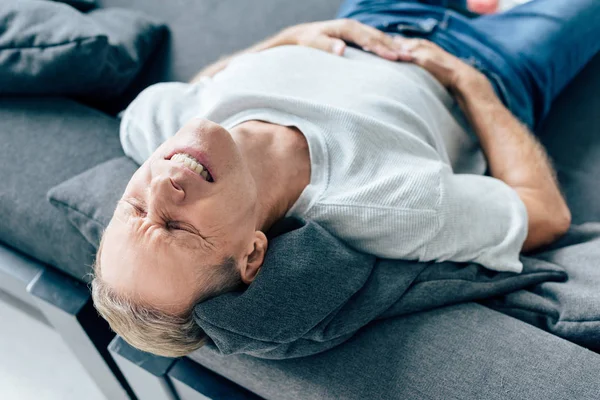 Vista de ángulo alto del hombre guapo en camiseta con dolor de estómago - foto de stock