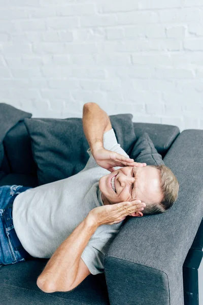 Hochwinkelaufnahme eines gutaussehenden Mannes im T-Shirt mit geschlossenen Augen, der den Kopf in der Wohnung berührt — Stockfoto