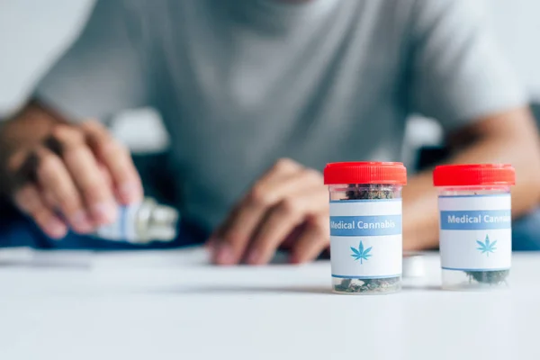 Enfoque selectivo de botellas con cannabis medicinal en la mesa - foto de stock