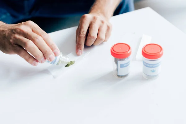 Cropped view of man in t-shirt rolling blunt in apartment — Stock Photo