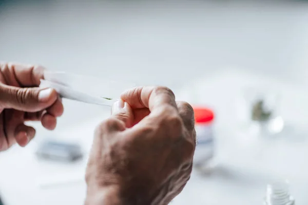 Ausgeschnittene Ansicht eines Mannes, der stumpf mit medizinischem Cannabis rollte — Stockfoto