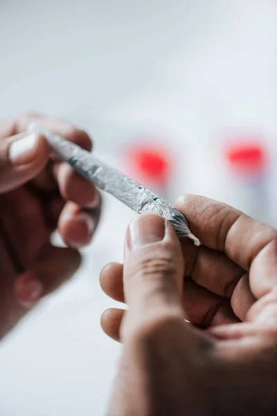 Vista recortada del hombre rodando romo con cannabis medicinal - foto de stock