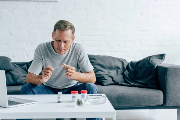 Handsome man in t-shirt rolling blunt with medical cannabis — Stock Photo