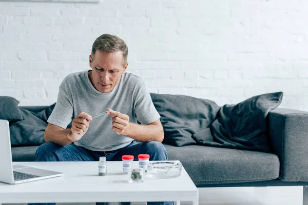 Homem bonito em t-shirt rolando contundente com cannabis medicinal — Fotografia de Stock