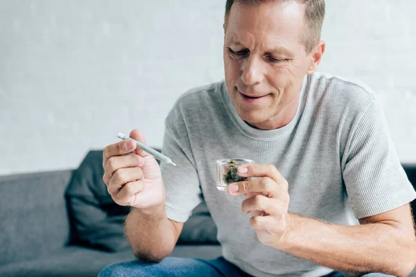 Hombre guapo en camiseta sosteniendo cannabis romo y medicinal - foto de stock