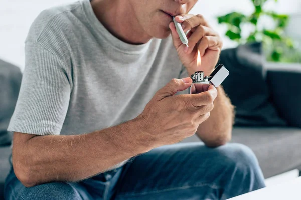 Cropped view of man in t-shirt lighting up blunt with medical cannabis — Stock Photo