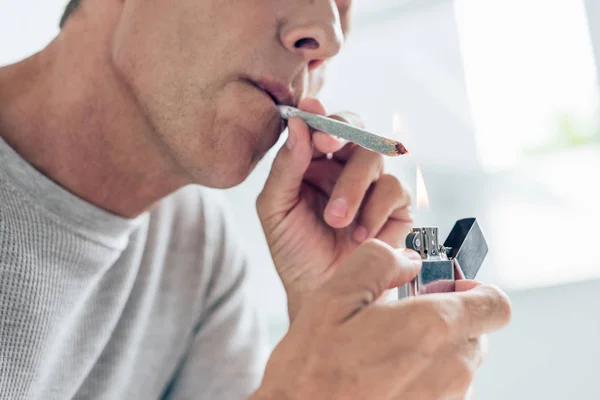 Cropped view of man lighting up blunt with medical cannabis — Stock Photo