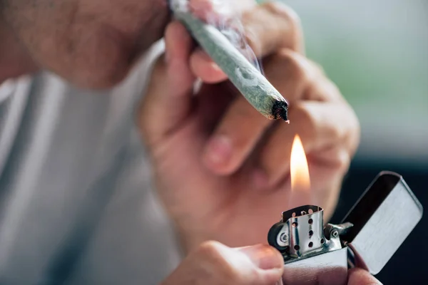 Vista recortada del hombre iluminando contundente con cannabis medicinal - foto de stock