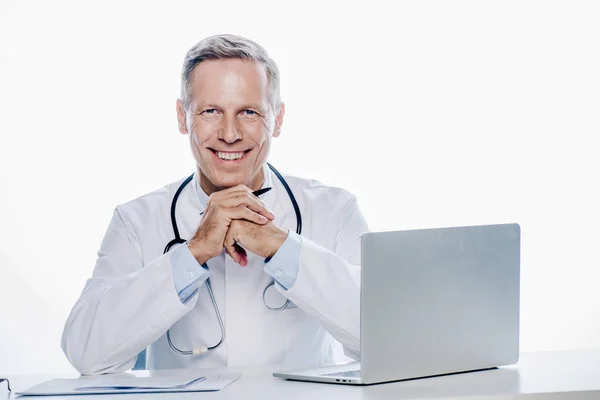Schöner Arzt in weißem Mantel, lächelnd und isoliert in die Kamera blickend — Stockfoto