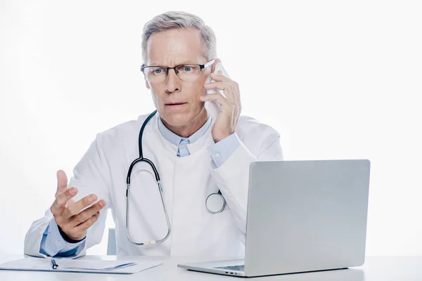 Handsome doctor in white coat talking on smartphone isolated on white — Stock Photo