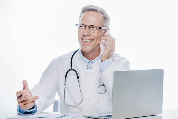 Schöner Arzt in weißem Mantel, der auf dem Smartphone isoliert auf weißem Grund spricht — Stockfoto