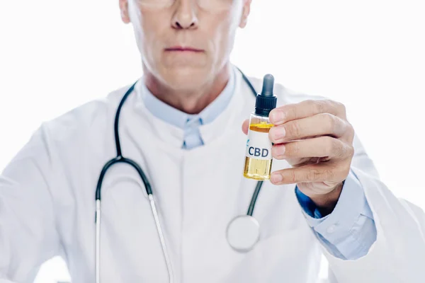 Cropped view of doctor in white coat holding cannabis oil isolated on white — Stock Photo