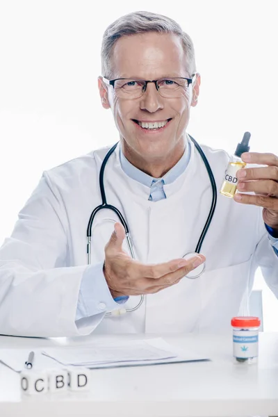 Красивый доктор в белом халате, держащий марихуану, изолированную на белом — стоковое фото