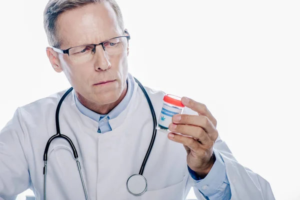 Guapo doctor en bata blanca sosteniendo cannabis medicinal aislado en blanco - foto de stock