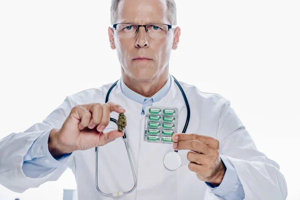 Красивий лікар у білому пальто тримає медичну марихуану і таблетки ізольовані на білому — стокове фото