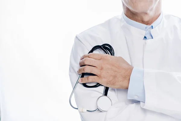 Vista recortada del médico de bata blanca sosteniendo estetoscopio aislado en blanco - foto de stock