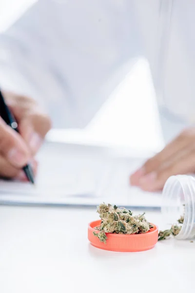 Foco seletivo de garrafa com cannabis medicinal na mesa branca — Fotografia de Stock