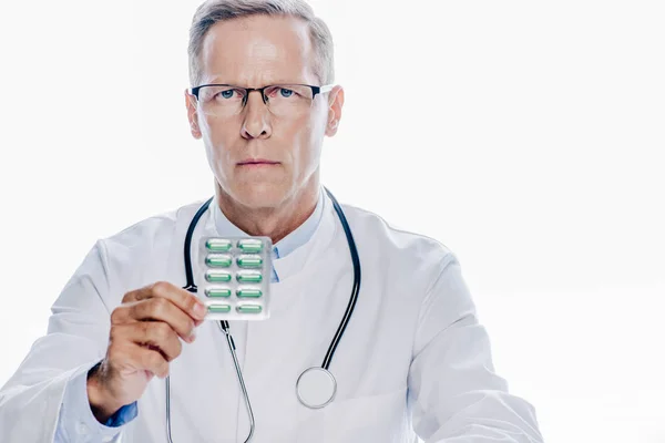 Красивый доктор в белом халате держит таблетки изолированы на белом — стоковое фото