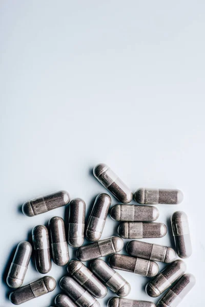 Top view of black pills on white background with copy space — Stock Photo