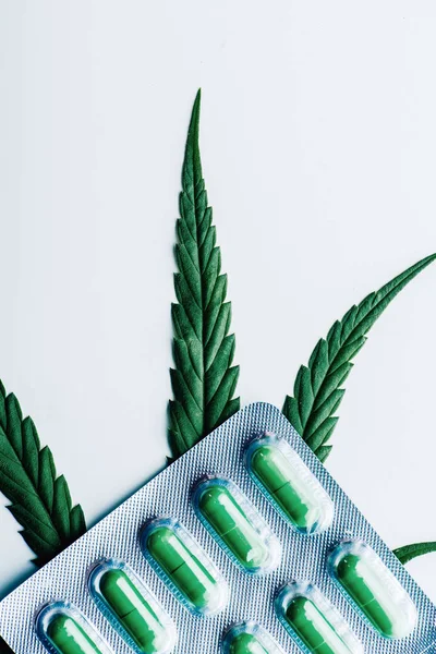 Green pills in blister and marijuana on white background — Stock Photo
