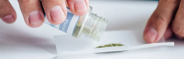 Tiro panorâmico de homem bonito derramando cannabis medicinal — Fotografia de Stock