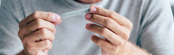Panoramic shot of man rolling blunt with medical cannabis — Stock Photo