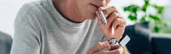 Panoramic shot of man lighting up blunt with medical cannabis — Stock Photo