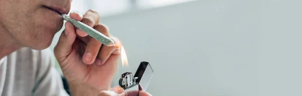 Panoramic shot of man lighting up blunt with medical cannabis — Stock Photo