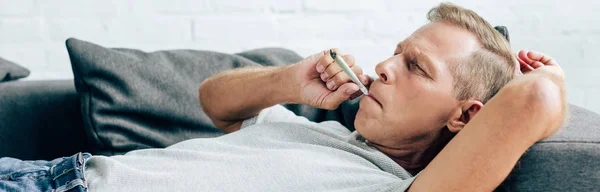 Panoramic shot of man smoking blunt with medical cannabis — Stock Photo