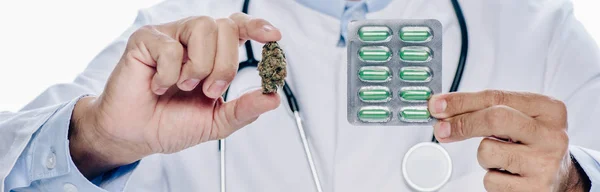 Colpo panoramico di medico in mantello bianco contenente cannabis medica e pillole isolate su bianco — Foto stock