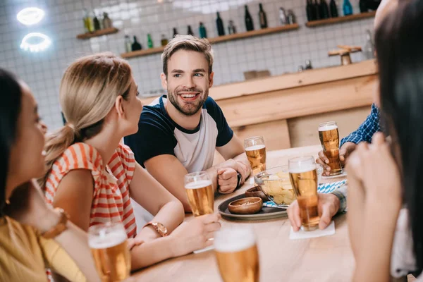 Amigos alegres hablando mientras pasan tiempo en el pub juntos - foto de stock