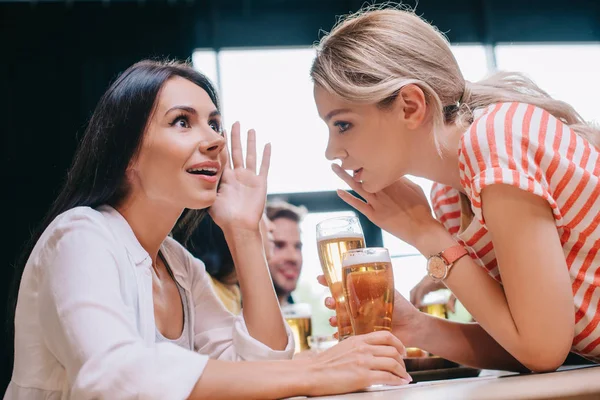 Young woman talking while sitting in pub with multicultural friends — Stock Photo