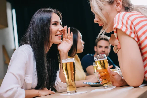Sonriente joven hablando mientras está sentado en el pub con amigos multiculturales - foto de stock