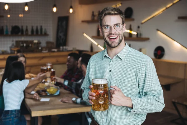 Bello giovane uomo in possesso di tazza di birra leggera e sorridente alla fotocamera — Foto stock