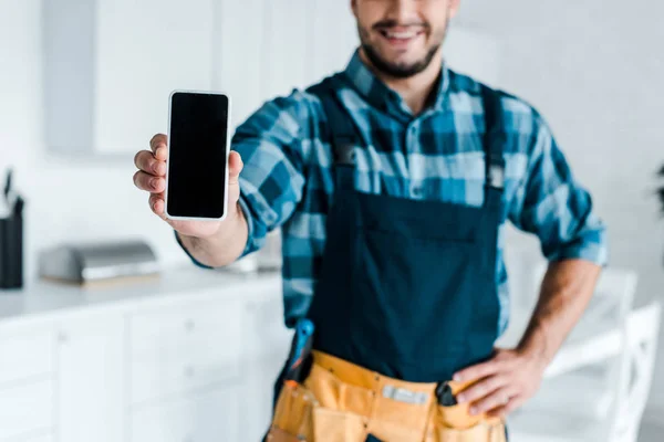 Cropped view of happy bearded handyman holding smartphone with blank screen — Stock Photo