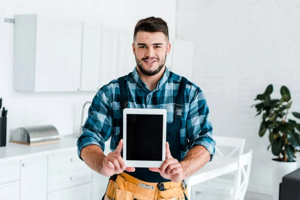 Happy handyman holding digital tablet with blank screen — Stock Photo