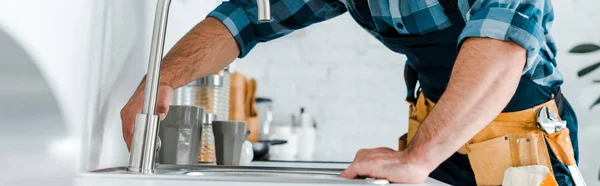 Panoramic shot of handyman working near sink in kitchen — Stock Photo