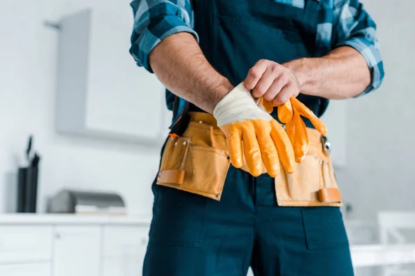 Cropped view of handyman in uniform wearing rubber glove — Stock Photo