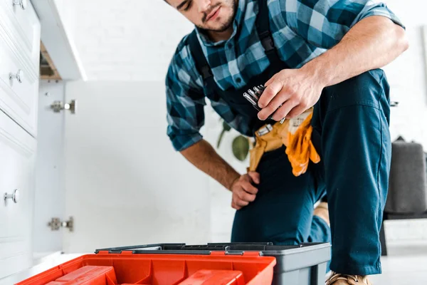 Vue recadrée de bricoleur regardant des outils près de la boîte à outils ouverte dans la cuisine — Photo de stock