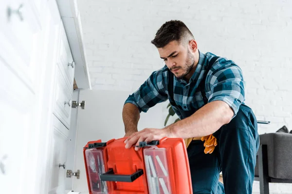 Enfoque selectivo de manitas guapo mirando la caja de herramientas abierta en la cocina — Stock Photo