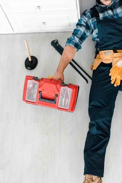 Vista superior del trabajador acostado en el suelo y trabajando cerca de la caja de herramientas — Stock Photo