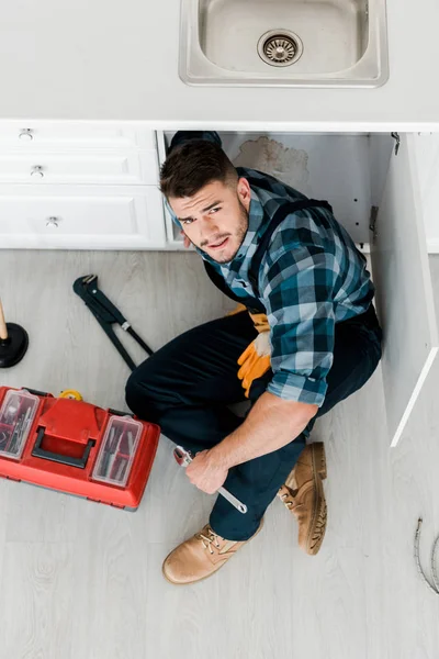 Draufsicht auf bärtige Handwerker, die auf dem Boden in der Nähe von Werkzeugkiste und Werkzeug sitzen — Stockfoto