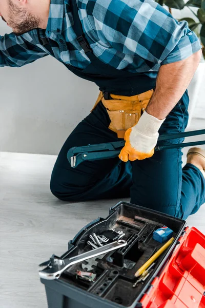 Cropped view of handyman working near kitchen cabinet and toolbox with instruments — Stock Photo